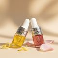 Two skincare droppers with rose elixir on a beige background